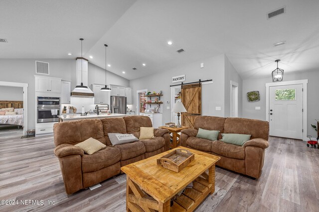 living area with a barn door, light wood-type flooring, and visible vents