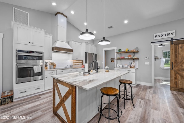 kitchen featuring a barn door, visible vents, custom exhaust hood, stainless steel appliances, and open shelves