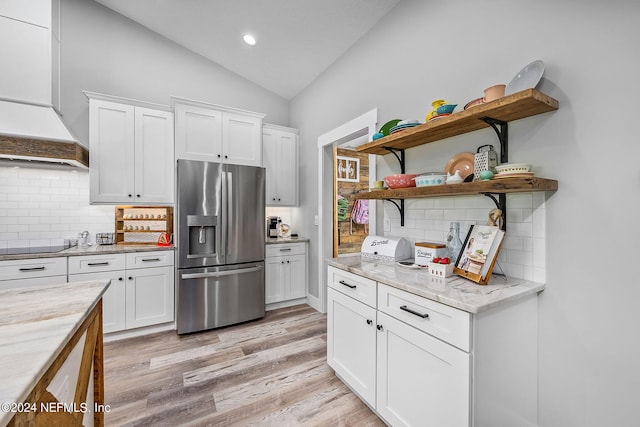 kitchen with stainless steel refrigerator with ice dispenser, light wood finished floors, open shelves, lofted ceiling, and white cabinets