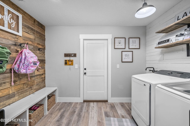 laundry area with laundry area, wood walls, light wood-type flooring, and washer and dryer