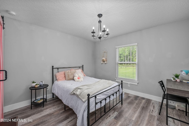 bedroom with an inviting chandelier, a textured ceiling, baseboards, and wood finished floors