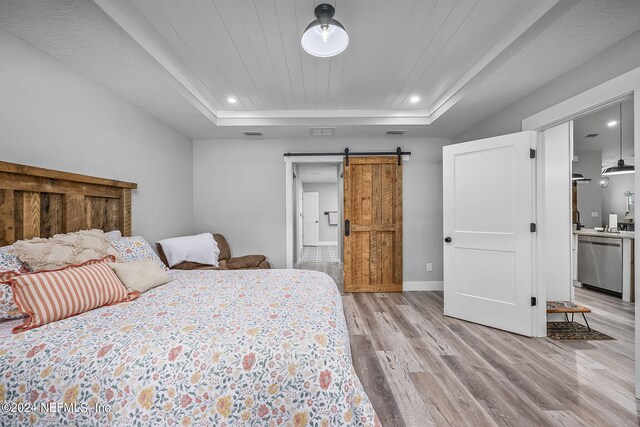 bedroom with a barn door, recessed lighting, wood ceiling, light wood finished floors, and a raised ceiling