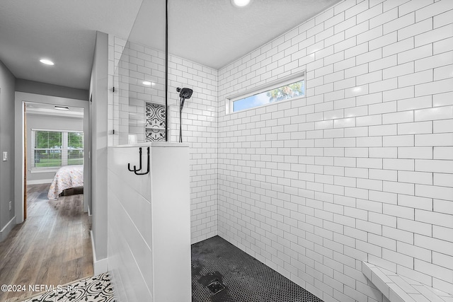 full bathroom featuring connected bathroom, baseboards, tiled shower, and wood finished floors