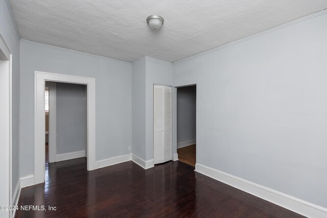 unfurnished bedroom with ornamental molding, a textured ceiling, a closet, and dark hardwood / wood-style flooring