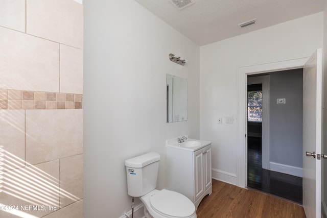 bathroom with vanity, a textured ceiling, hardwood / wood-style floors, and toilet