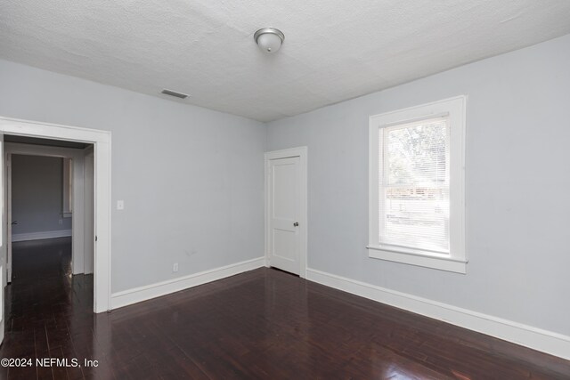 empty room with a textured ceiling and dark wood-type flooring