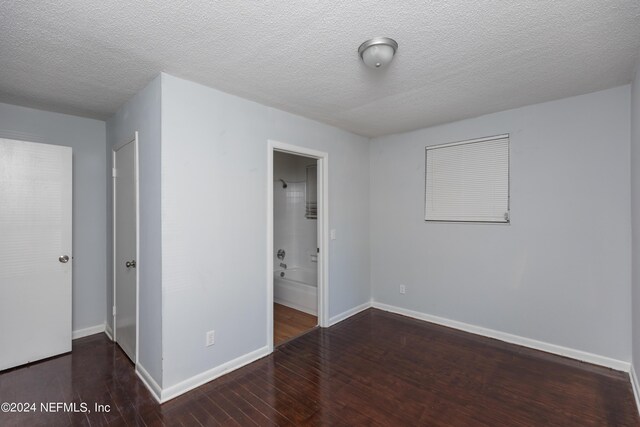 spare room with a textured ceiling and dark hardwood / wood-style flooring