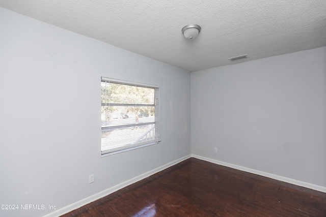 empty room featuring a textured ceiling and dark hardwood / wood-style floors