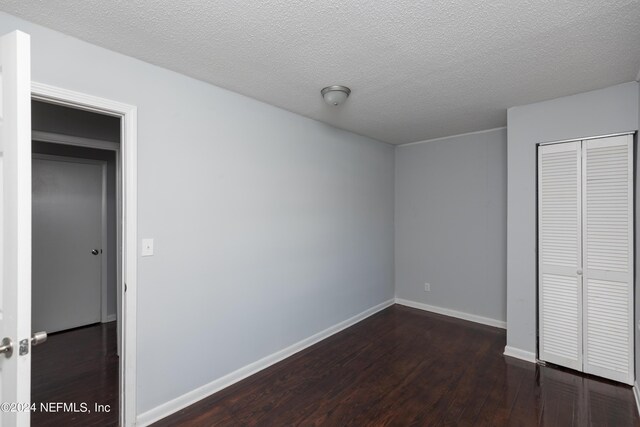 unfurnished bedroom with a closet, dark wood-type flooring, and a textured ceiling