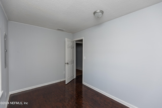 spare room with a textured ceiling and dark hardwood / wood-style floors