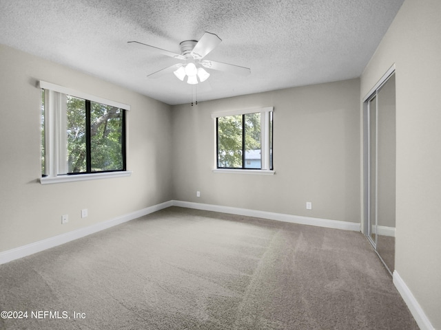 empty room with ceiling fan, carpet floors, and a textured ceiling