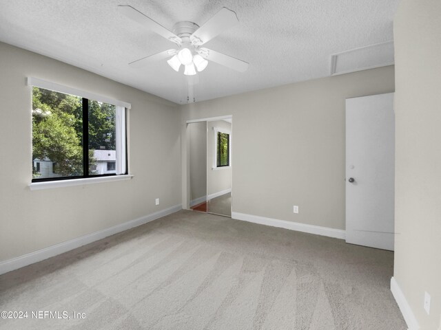 unfurnished room with ceiling fan, carpet flooring, and a textured ceiling