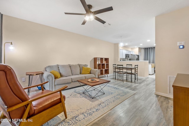 living room with light hardwood / wood-style flooring and ceiling fan