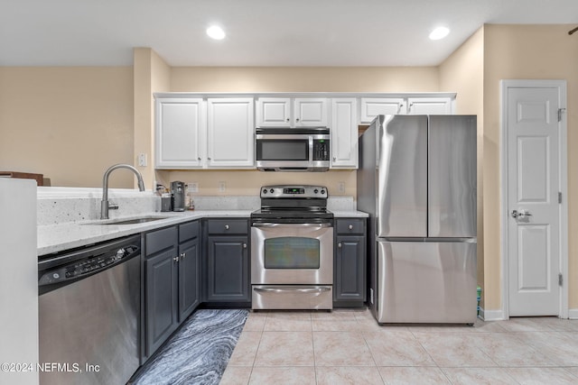 kitchen featuring appliances with stainless steel finishes, sink, gray cabinets, light tile patterned flooring, and white cabinetry