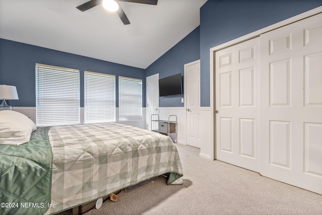 carpeted bedroom with a closet, lofted ceiling, and ceiling fan