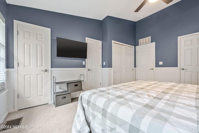 bedroom with two closets, carpet, and ceiling fan