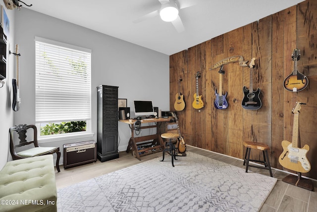 office space with light hardwood / wood-style flooring, ceiling fan, and wood walls