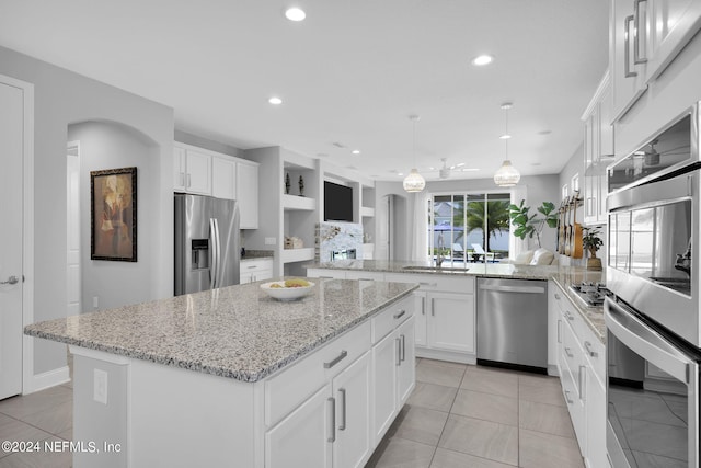 kitchen with pendant lighting, appliances with stainless steel finishes, white cabinetry, a center island, and kitchen peninsula