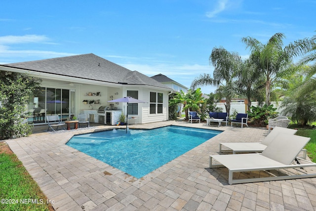 view of swimming pool featuring a patio and an outdoor kitchen