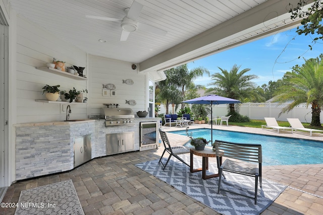 view of swimming pool with sink, a patio area, area for grilling, ceiling fan, and exterior kitchen