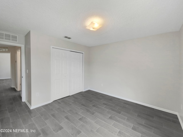 unfurnished bedroom featuring wood-type flooring, a closet, and a textured ceiling