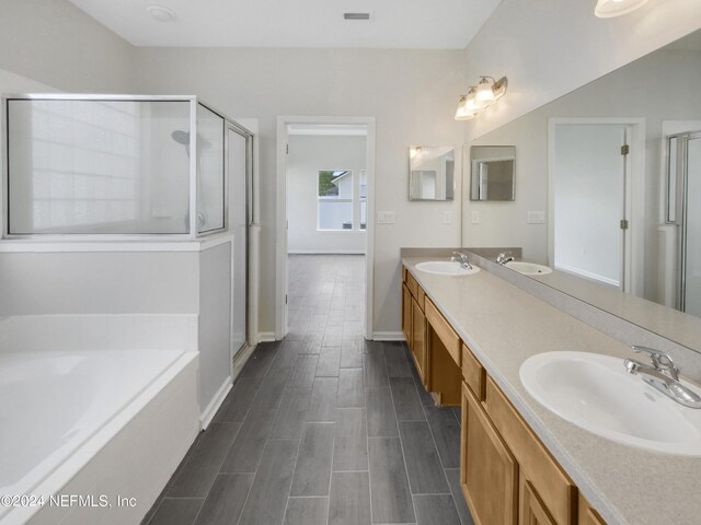 bathroom featuring shower with separate bathtub and dual bowl vanity