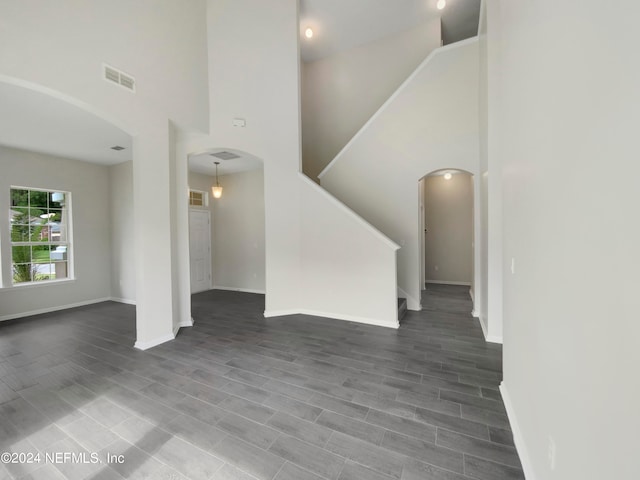 unfurnished living room featuring hardwood / wood-style flooring and a towering ceiling