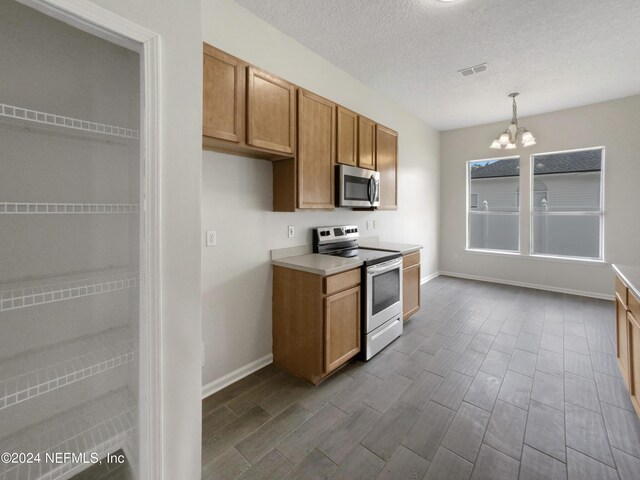 kitchen featuring range with electric stovetop, hanging light fixtures, a textured ceiling, a chandelier, and hardwood / wood-style flooring