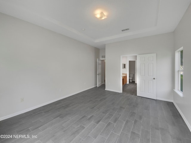 unfurnished bedroom with hardwood / wood-style flooring and a raised ceiling