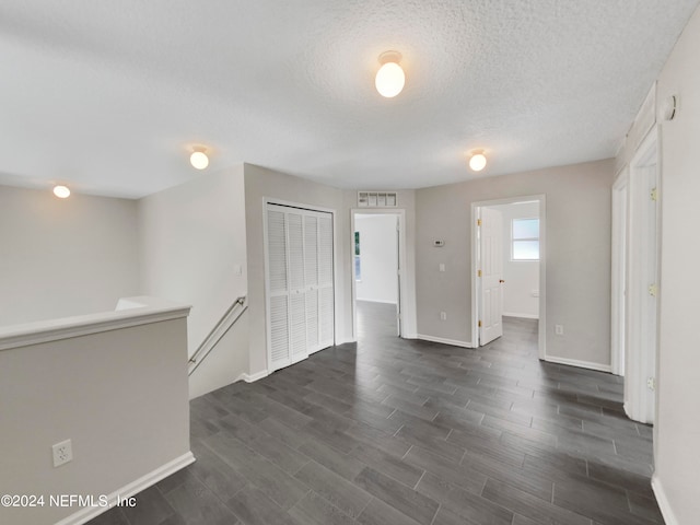 empty room featuring dark wood-type flooring and a textured ceiling