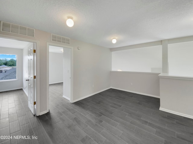 spare room with dark wood-type flooring and a textured ceiling