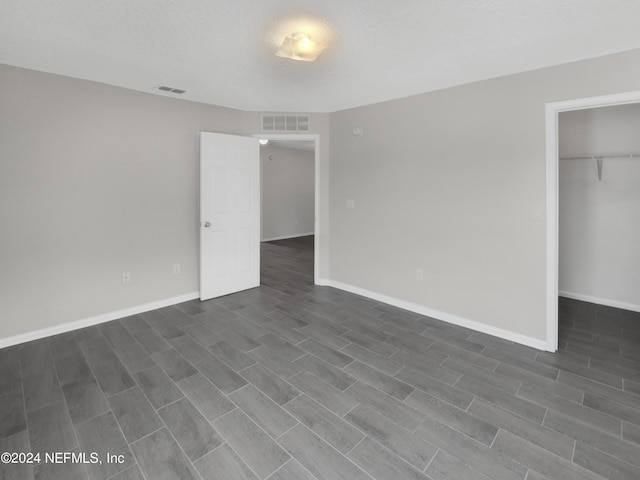 unfurnished bedroom featuring hardwood / wood-style floors, a textured ceiling, a closet, and a walk in closet