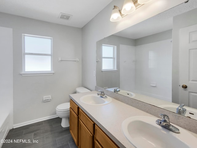 full bathroom featuring a healthy amount of sunlight, bathtub / shower combination, dual bowl vanity, and toilet