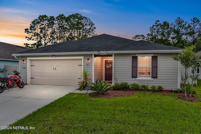 ranch-style home with a garage, concrete driveway, and a front lawn