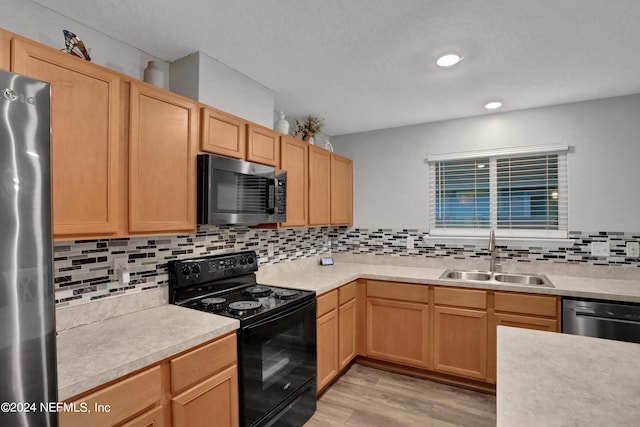 kitchen featuring tasteful backsplash, stainless steel appliances, sink, light brown cabinets, and light wood-type flooring