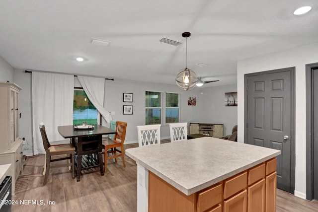 kitchen featuring dishwasher, a kitchen island, hanging light fixtures, and light wood-type flooring