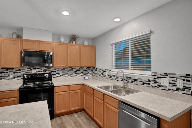 kitchen with sink, appliances with stainless steel finishes, light wood-type flooring, and decorative backsplash