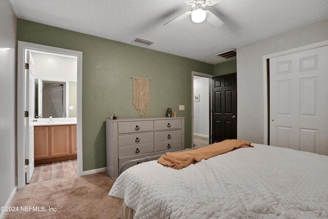 bedroom with ensuite bath, ceiling fan, light colored carpet, a closet, and sink