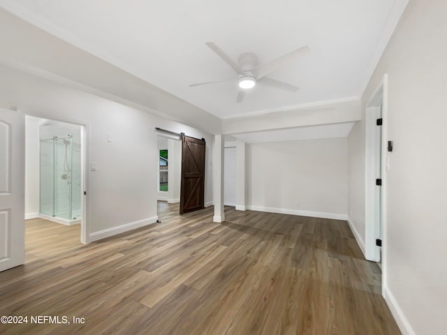 spare room with wood-type flooring, a barn door, and ceiling fan