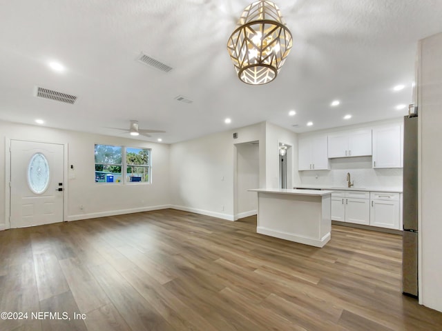 kitchen with white cabinetry, hanging light fixtures, ceiling fan with notable chandelier, light wood-type flooring, and stainless steel refrigerator