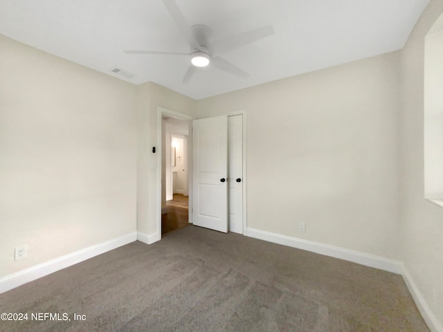 unfurnished bedroom with dark carpet and ceiling fan