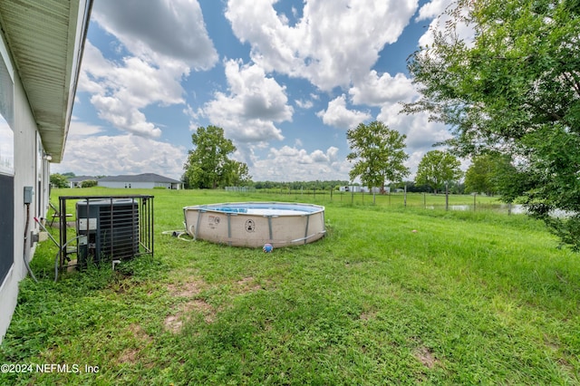 view of yard featuring central AC unit, a fenced in pool, and a rural view