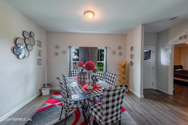 dining room with hardwood / wood-style floors and a textured ceiling