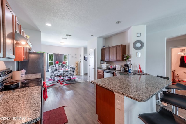 kitchen with sink, dark wood-type flooring, a kitchen breakfast bar, stainless steel appliances, and kitchen peninsula