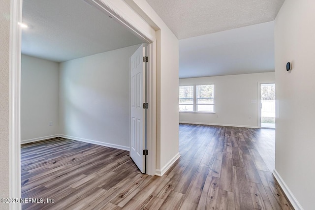 corridor featuring light wood-type flooring and a textured ceiling