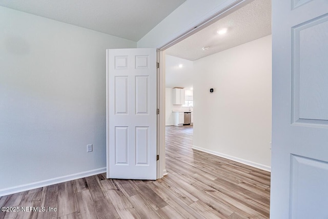 spare room featuring a textured ceiling and light hardwood / wood-style floors