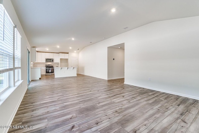 unfurnished living room featuring light wood-type flooring and vaulted ceiling