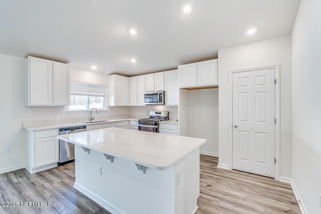 kitchen with a center island, white cabinetry, stainless steel appliances, sink, and a kitchen breakfast bar