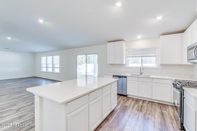 kitchen with sink, white cabinets, appliances with stainless steel finishes, and a center island