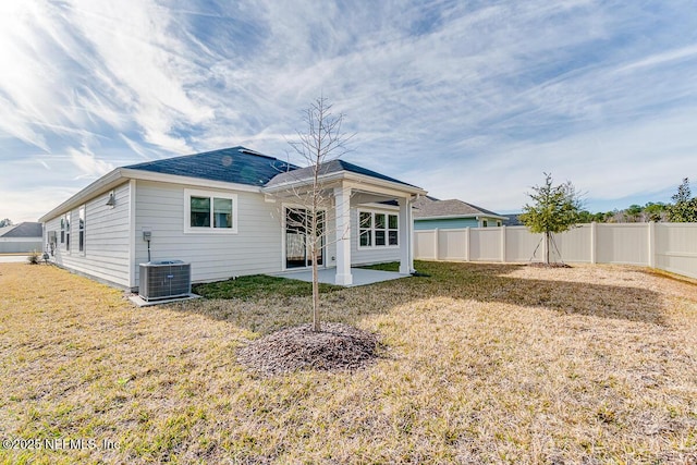 rear view of property featuring a patio area, a lawn, and central AC